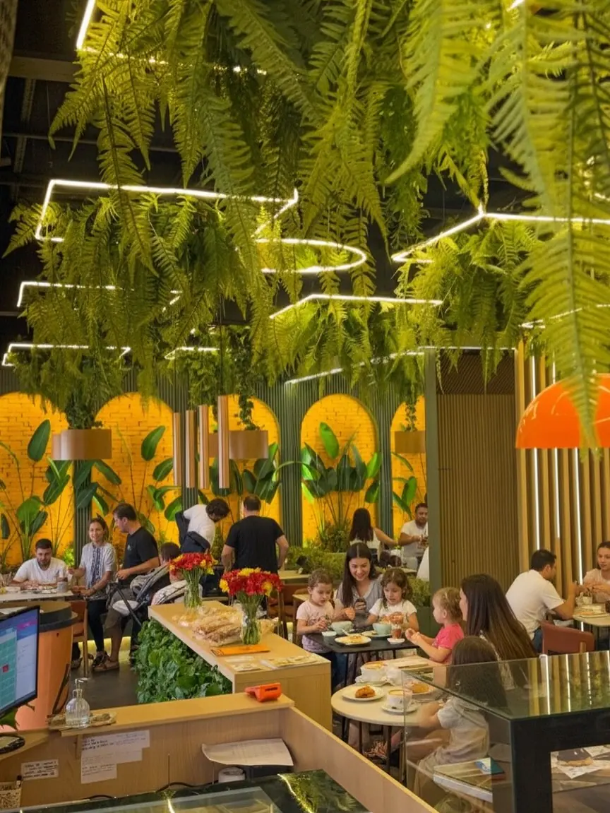 Salão da Bio Bakery à noite, com samambaias suspensas e luz quente